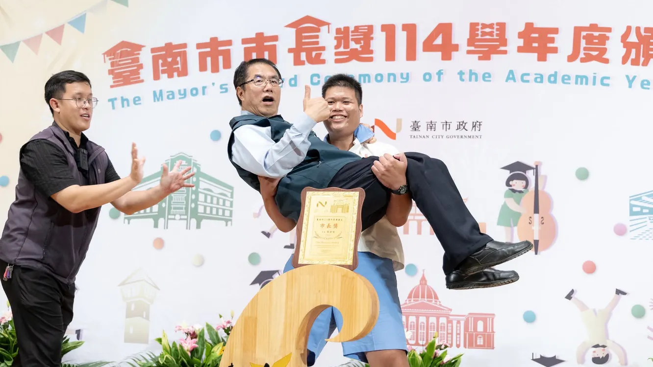 ▲市長陪你拍,不少學生搶著抱市長,一旁隨扈(左)繃緊神經,表情意外在網路城討論焦點。(圖/翻攝潘俊霖臉書)